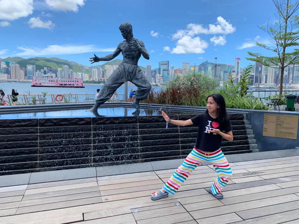 Mia practicing shuto uke by a Bruce Lee statue in Hong Kong